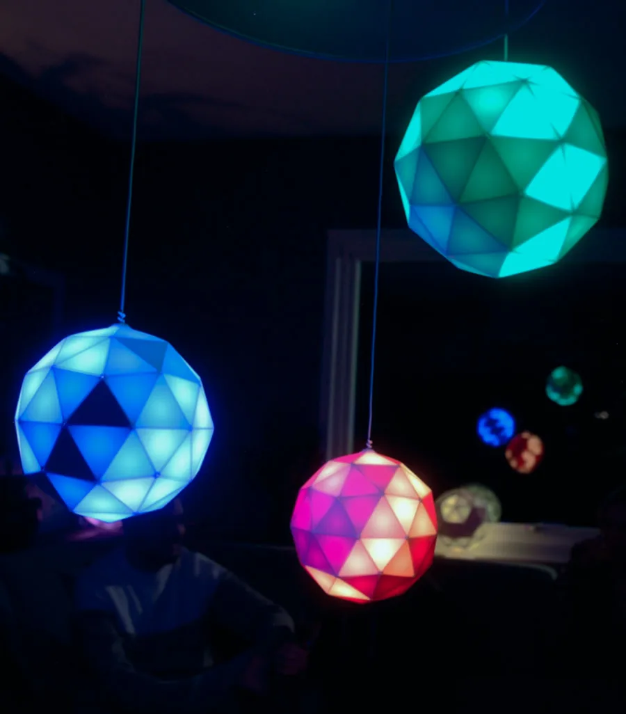 Three GLORBs hung as pendant lights above a party
